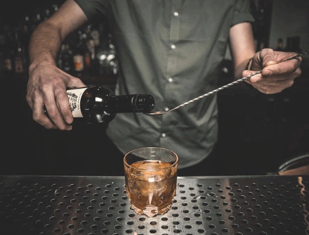 bartender adds bitter into drink
