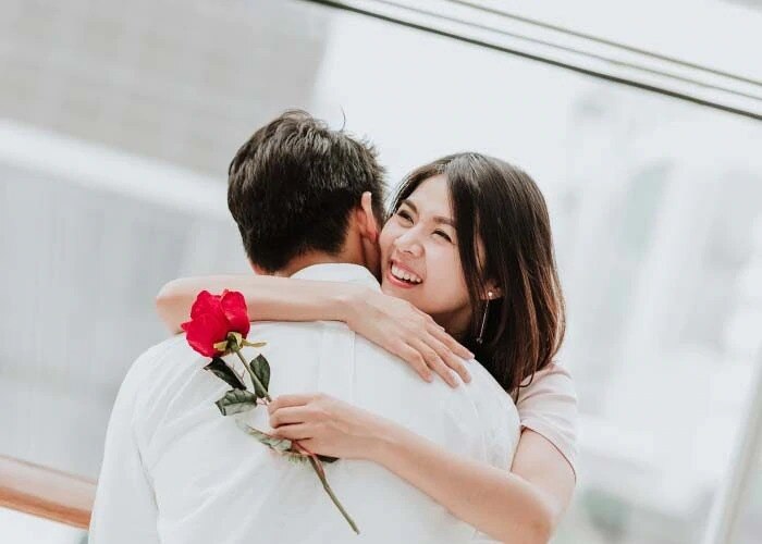 asian woman with rose hugs man