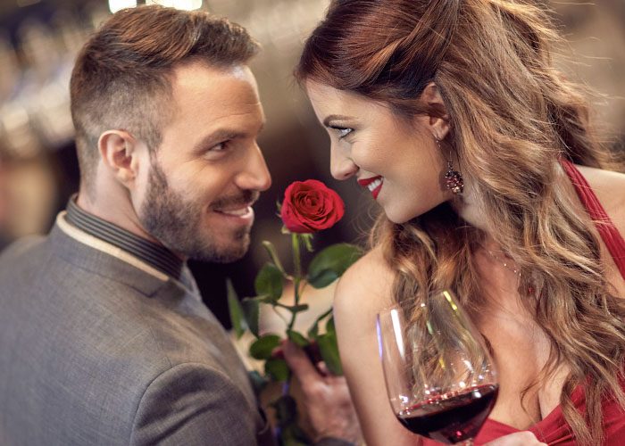 man with rose and woman with glass of wine