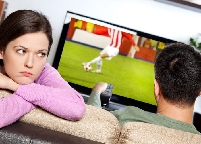 man watching footbal with sad girlfriend