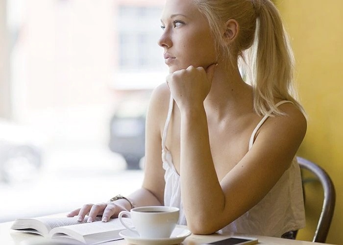 woman with book drinks coffee