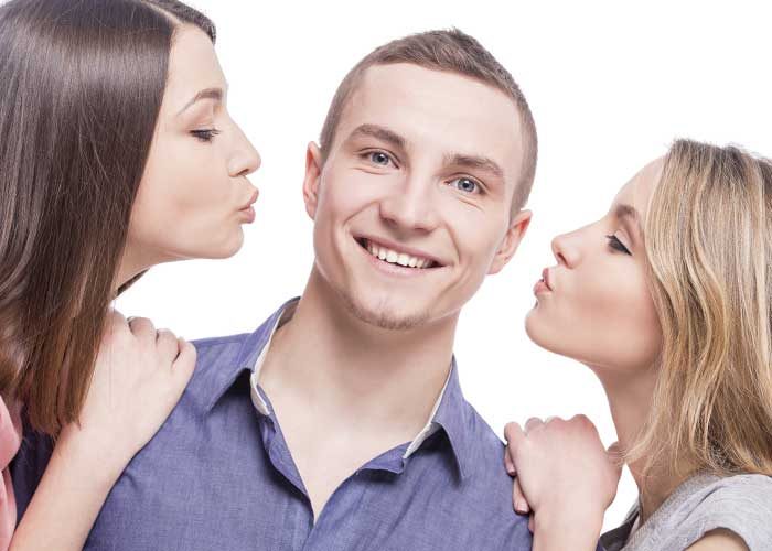 2 women trying to kiss man